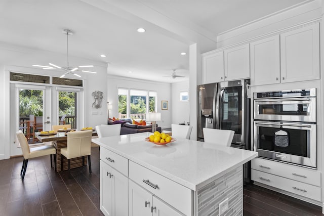 kitchen featuring a kitchen island, stainless steel appliances, white cabinets, crown molding, and dark wood-style flooring