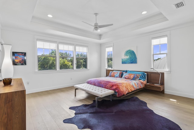 bedroom featuring visible vents, a raised ceiling, baseboards, and wood finished floors