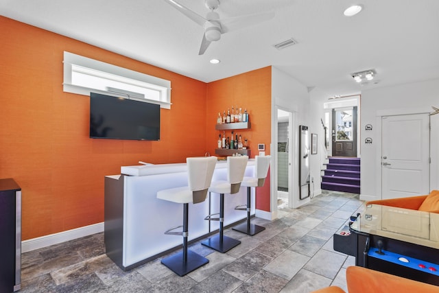 bar featuring baseboards, visible vents, stairs, stone finish floor, and a dry bar