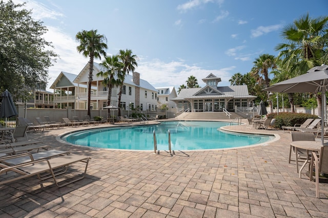 pool with a patio area, fence, and a residential view