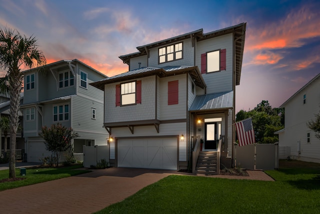 view of front facade featuring a gate, a standing seam roof, a garage, decorative driveway, and metal roof