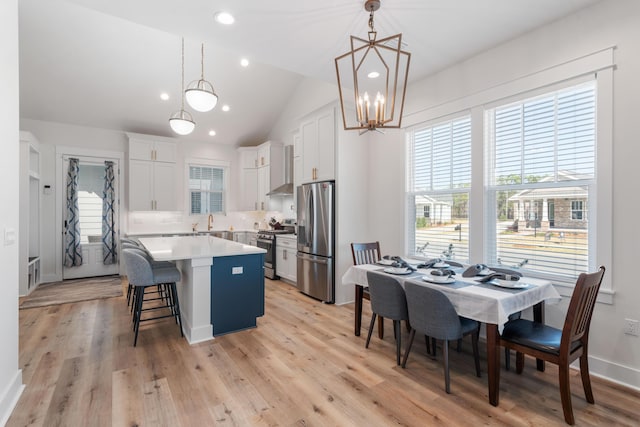 kitchen with a kitchen island, plenty of natural light, a sink, appliances with stainless steel finishes, and white cabinetry