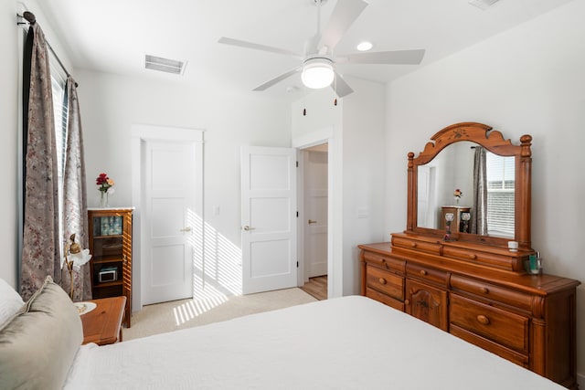 bedroom with light colored carpet, a ceiling fan, and visible vents