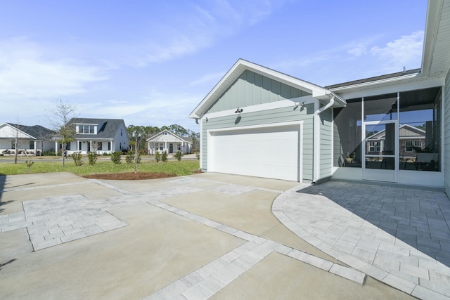 view of property exterior with concrete driveway, an attached garage, board and batten siding, and a residential view