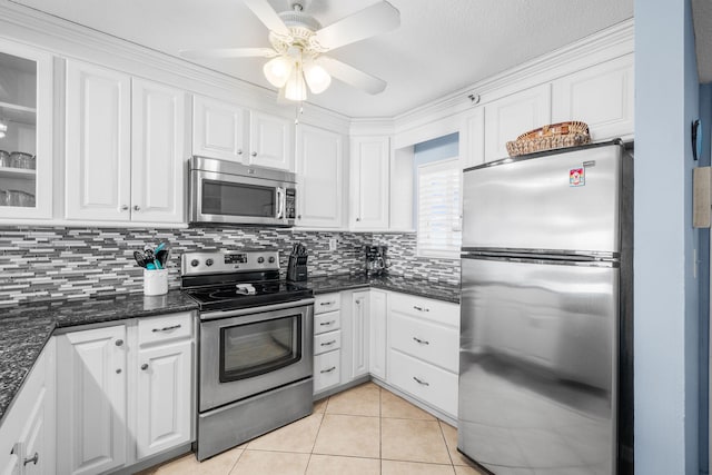 kitchen featuring light tile patterned flooring, white cabinets, appliances with stainless steel finishes, backsplash, and glass insert cabinets