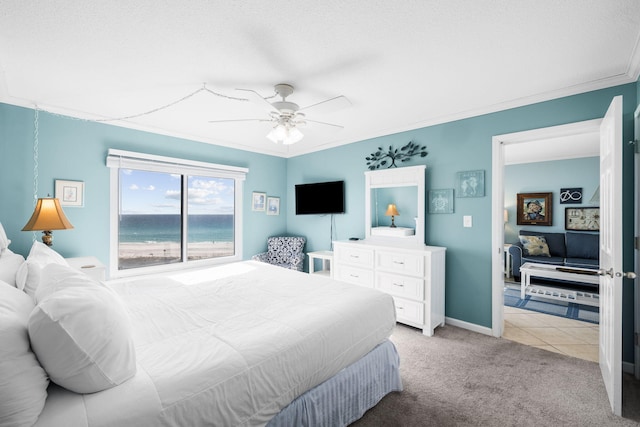 bedroom featuring light tile patterned floors, light colored carpet, ornamental molding, ceiling fan, and baseboards