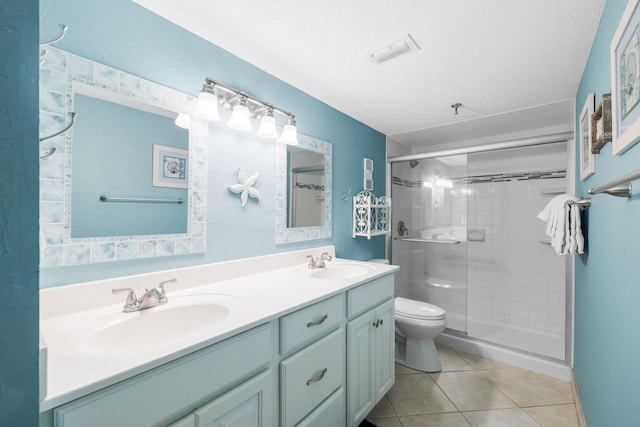 full bath with toilet, a sink, a shower stall, a textured ceiling, and tile patterned floors