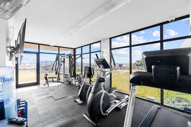 gym with floor to ceiling windows and a textured ceiling