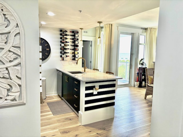 bar featuring decorative light fixtures, visible vents, light wood-style flooring, a sink, and dishwasher