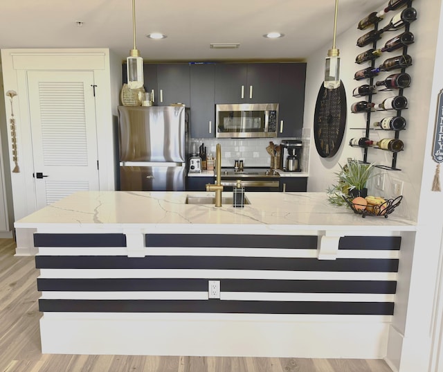 kitchen featuring light wood finished floors, visible vents, decorative backsplash, appliances with stainless steel finishes, and decorative light fixtures