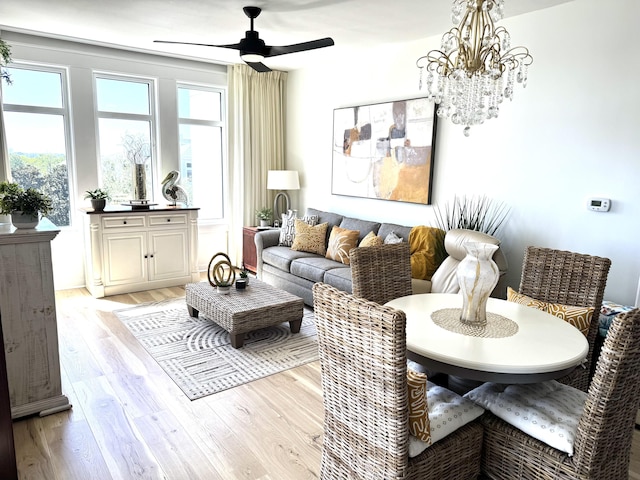 living area featuring light wood finished floors and ceiling fan with notable chandelier