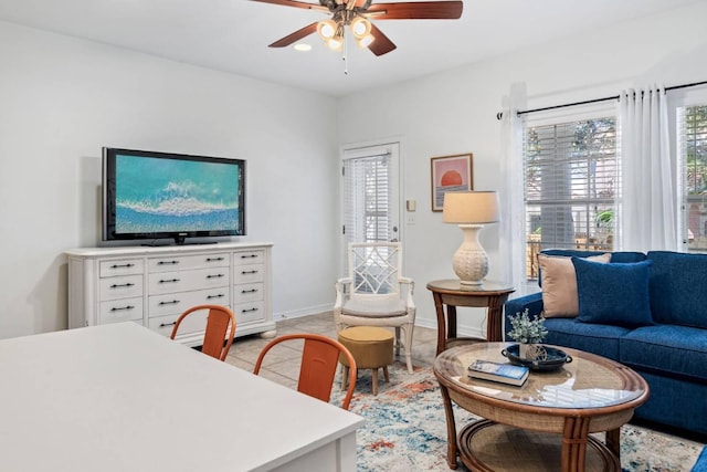 living area featuring light tile patterned floors, baseboards, a ceiling fan, and a healthy amount of sunlight