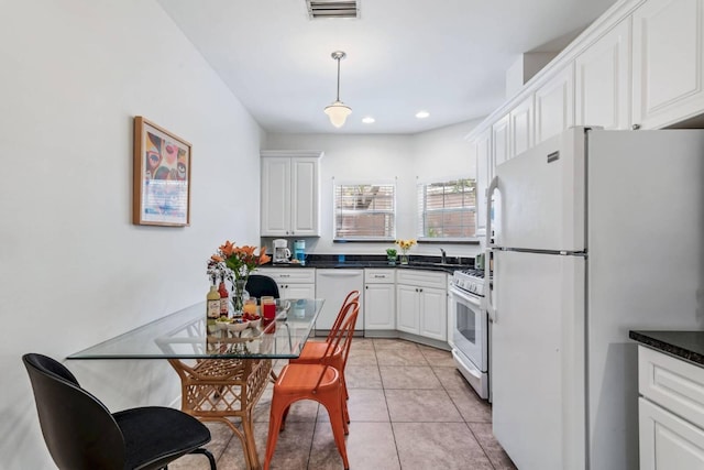 kitchen featuring light tile patterned floors, dark countertops, visible vents, white cabinets, and white appliances