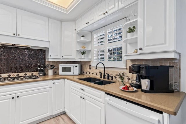 kitchen with under cabinet range hood, white appliances, a sink, open shelves, and tasteful backsplash