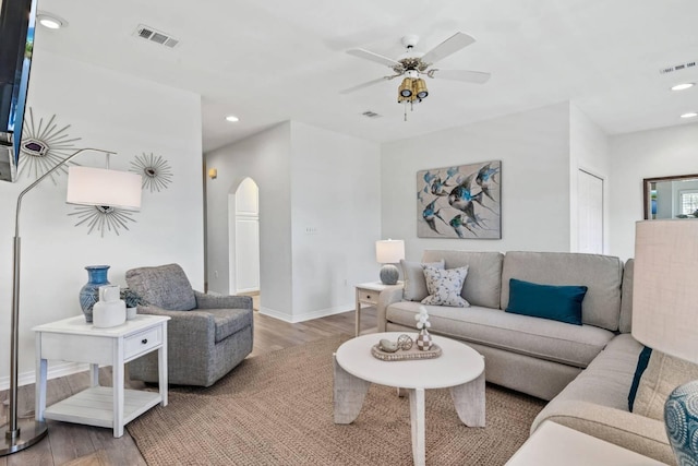 living area featuring arched walkways, wood finished floors, and visible vents