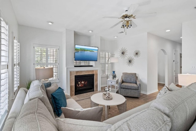 living area featuring baseboards, arched walkways, a tile fireplace, wood finished floors, and recessed lighting