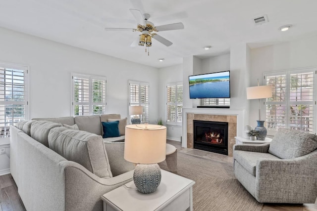 living area with a ceiling fan, visible vents, a fireplace, and wood finished floors