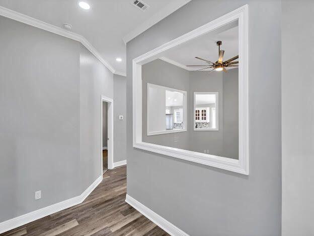 empty room with crown molding, visible vents, ceiling fan, wood finished floors, and baseboards