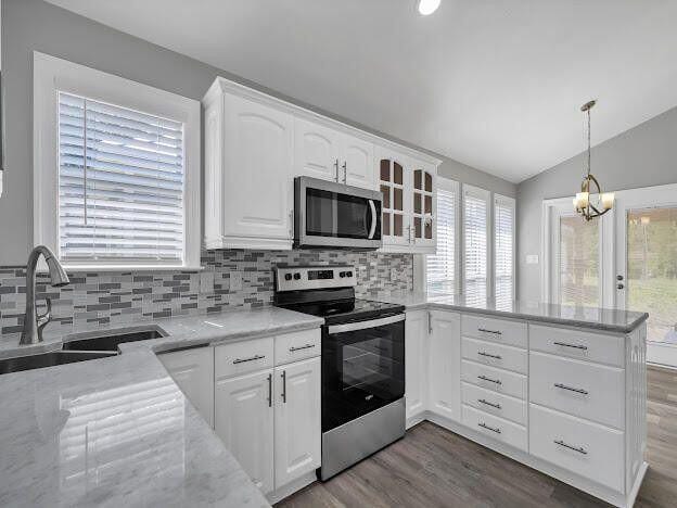 kitchen featuring white cabinets, a peninsula, vaulted ceiling, stainless steel appliances, and a sink