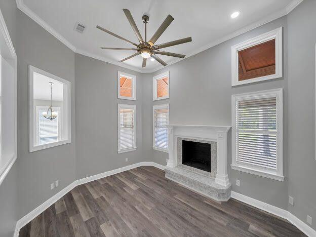 unfurnished living room with dark wood-style flooring, visible vents, crown molding, and baseboards