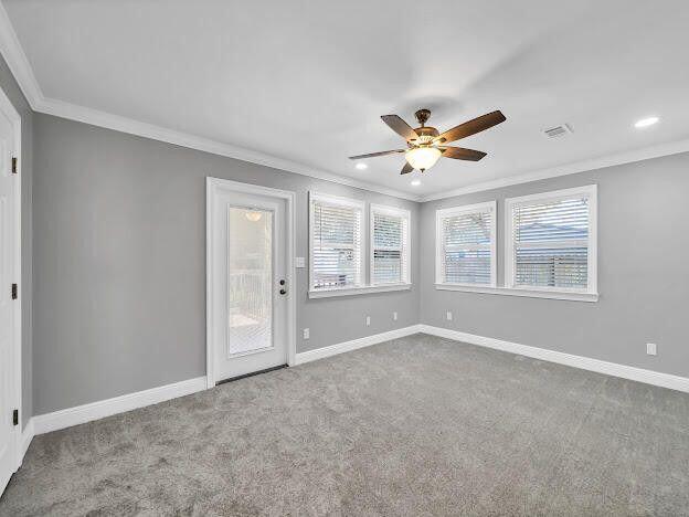 empty room with baseboards, visible vents, and crown molding