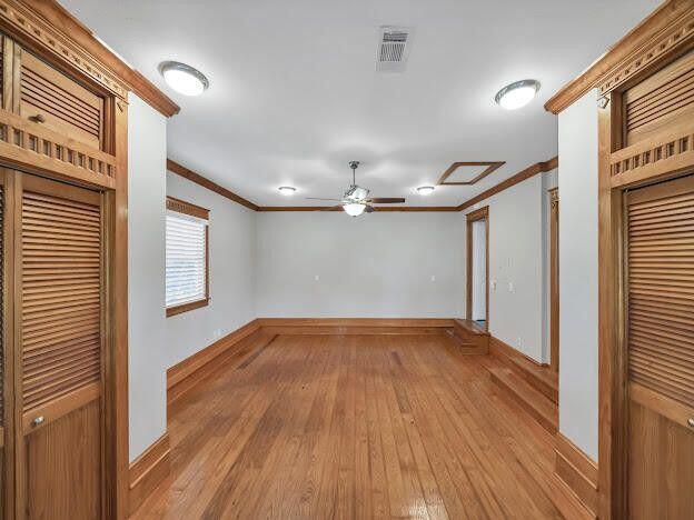 spare room featuring light wood-style flooring, visible vents, baseboards, and ornamental molding