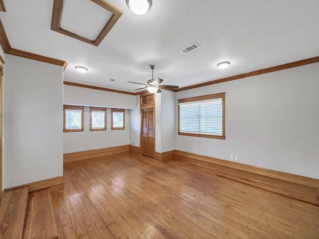 unfurnished room featuring crown molding, a wealth of natural light, visible vents, attic access, and light wood-type flooring