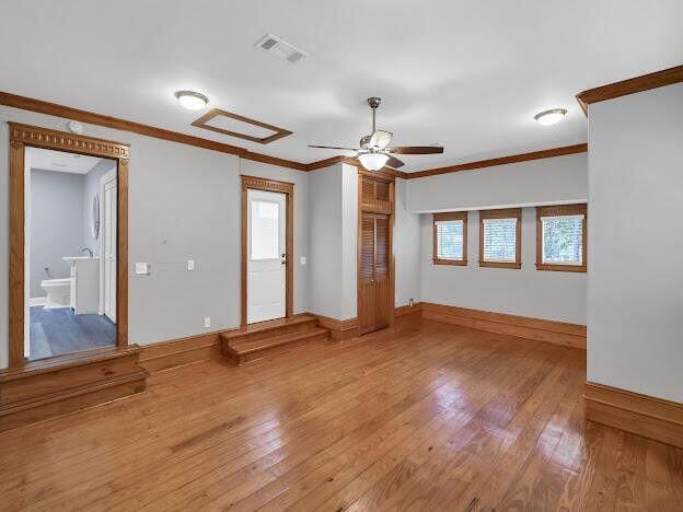 spare room with ornamental molding, a healthy amount of sunlight, visible vents, and hardwood / wood-style flooring