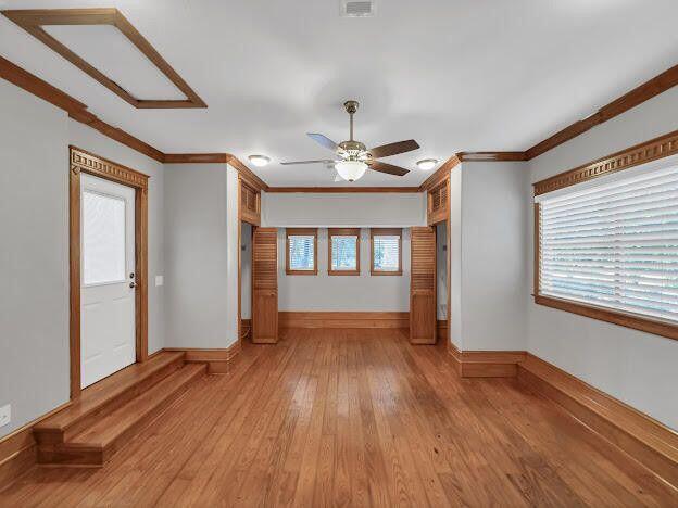 unfurnished living room featuring ornamental molding, a wealth of natural light, light wood-style floors, and baseboards