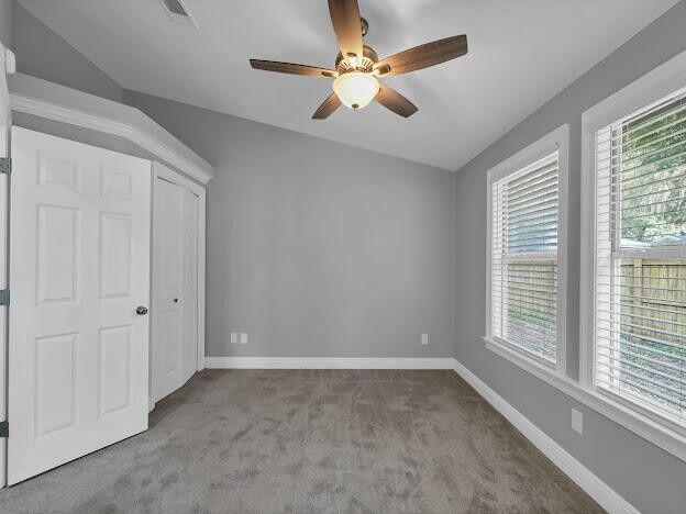 unfurnished bedroom with carpet floors, visible vents, baseboards, and ceiling fan