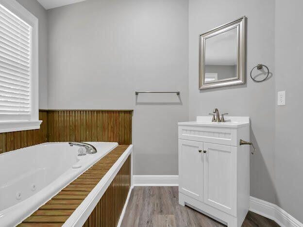 full bathroom featuring a whirlpool tub, wood finished floors, vanity, and baseboards