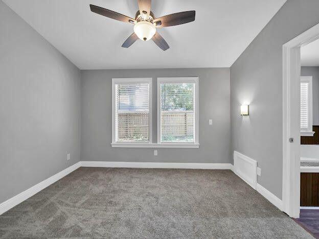 carpeted empty room with a ceiling fan, visible vents, and baseboards