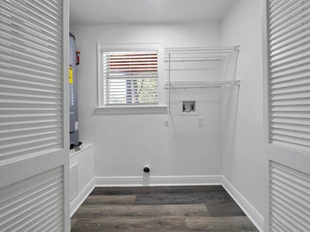 clothes washing area with dark wood-style flooring, washer hookup, laundry area, and baseboards