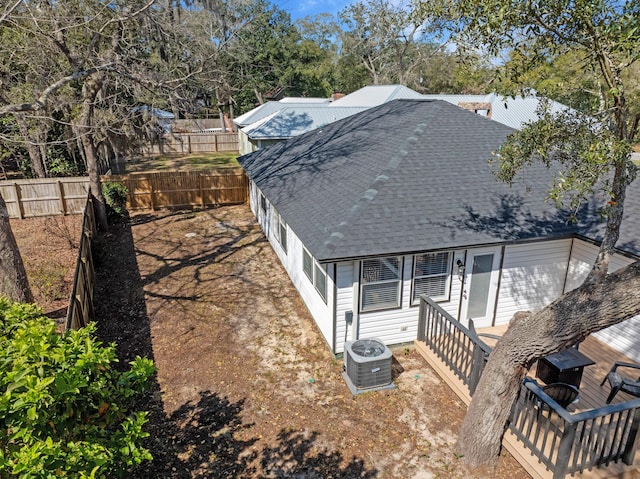 exterior space with roof with shingles, a fenced backyard, cooling unit, and a wooden deck