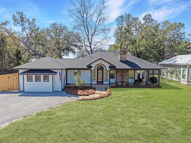 view of front of home featuring gravel driveway, roof with shingles, a chimney, fence, and a front lawn