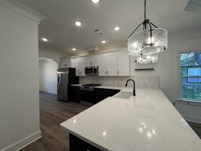 1575 Pine St, Niceville, FL 32578 - kitchen with stainless steel appliances, a sink, arched walkways, baseboards, and decorative backsplash