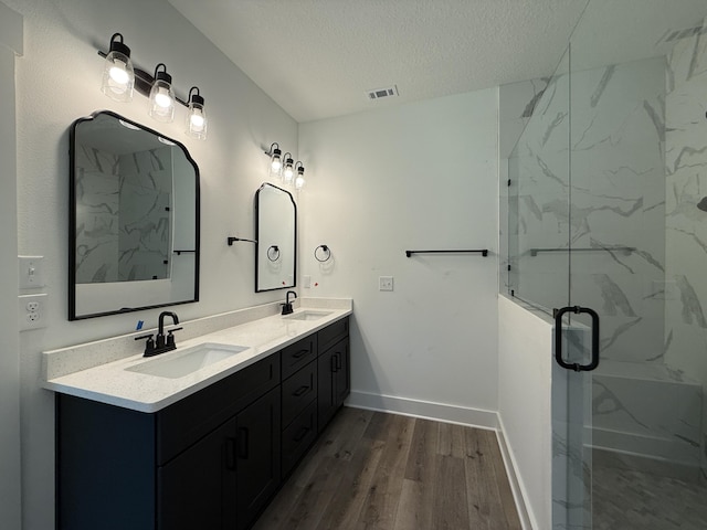 1575 Pine St, Niceville, FL 32578 - bathroom featuring wood finished floors, a marble finish shower, double vanity, a textured ceiling, and baseboards