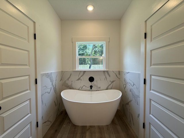 1575 Pine St, Niceville, FL 32578 - bathroom with tile walls, wood finished floors, a freestanding bath, wainscoting, and recessed lighting