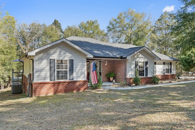 ranch-style house featuring roof with shingles, a front yard, cooling unit, and brick siding