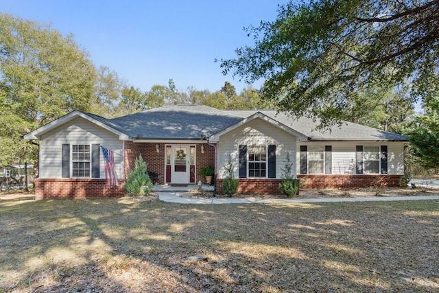 ranch-style house featuring a shingled roof, a front yard, and brick siding