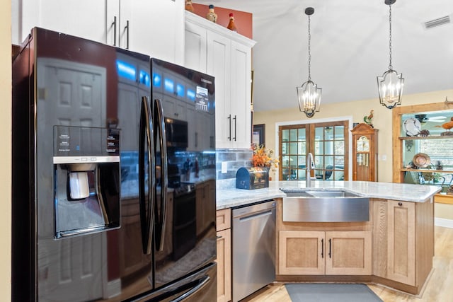 kitchen with light stone counters, a sink, visible vents, stainless steel dishwasher, and black fridge