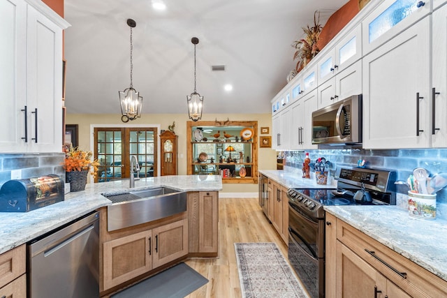 kitchen featuring visible vents, vaulted ceiling, stainless steel appliances, french doors, and a sink