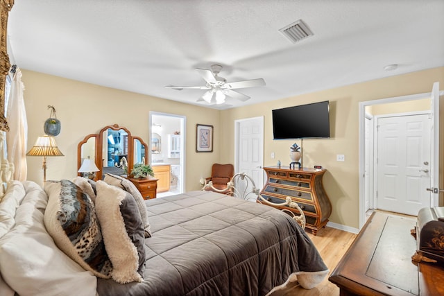 bedroom featuring visible vents, light wood-style flooring, ceiling fan, ensuite bath, and baseboards