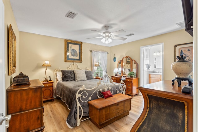 bedroom with light wood finished floors, ceiling fan, visible vents, and connected bathroom