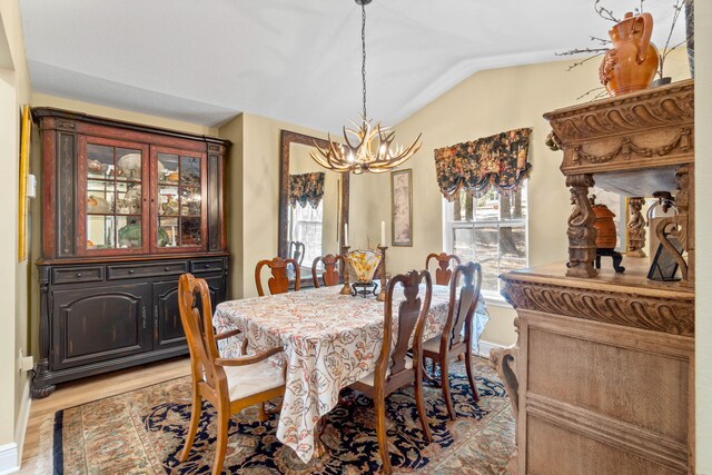 dining space featuring lofted ceiling, light wood finished floors, and a chandelier