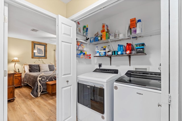 clothes washing area featuring light wood-type flooring, washing machine and dryer, laundry area, and visible vents