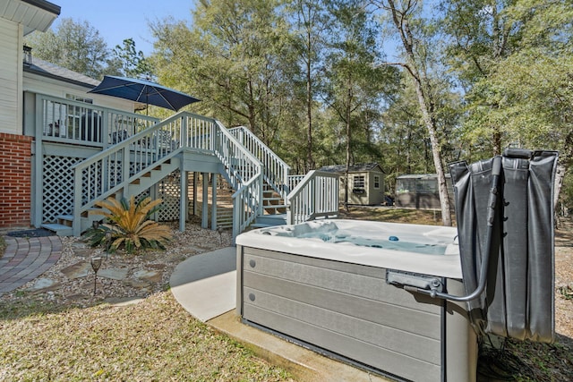 view of yard featuring a hot tub, stairway, an outbuilding, a storage unit, and a deck