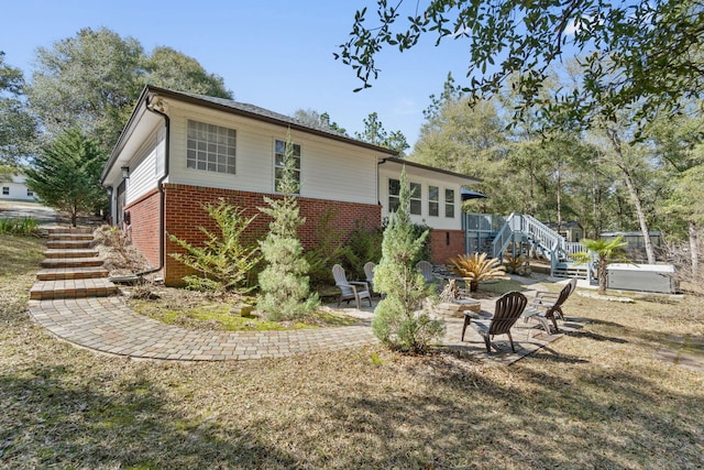 view of property exterior with stairs, a patio, and brick siding