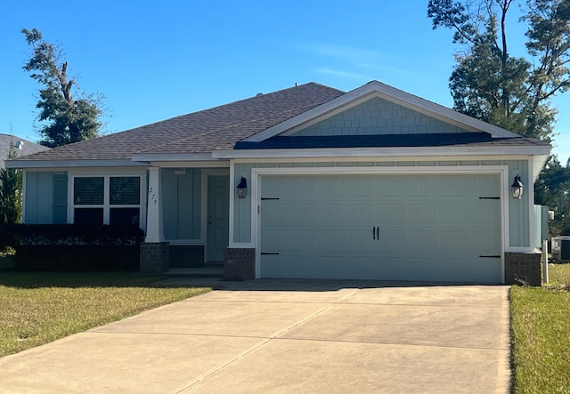 view of front of property featuring a garage, concrete driveway, a front yard, and a shingled roof