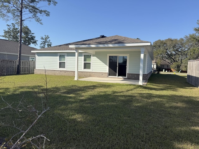 rear view of house with a patio area, a lawn, brick siding, and fence